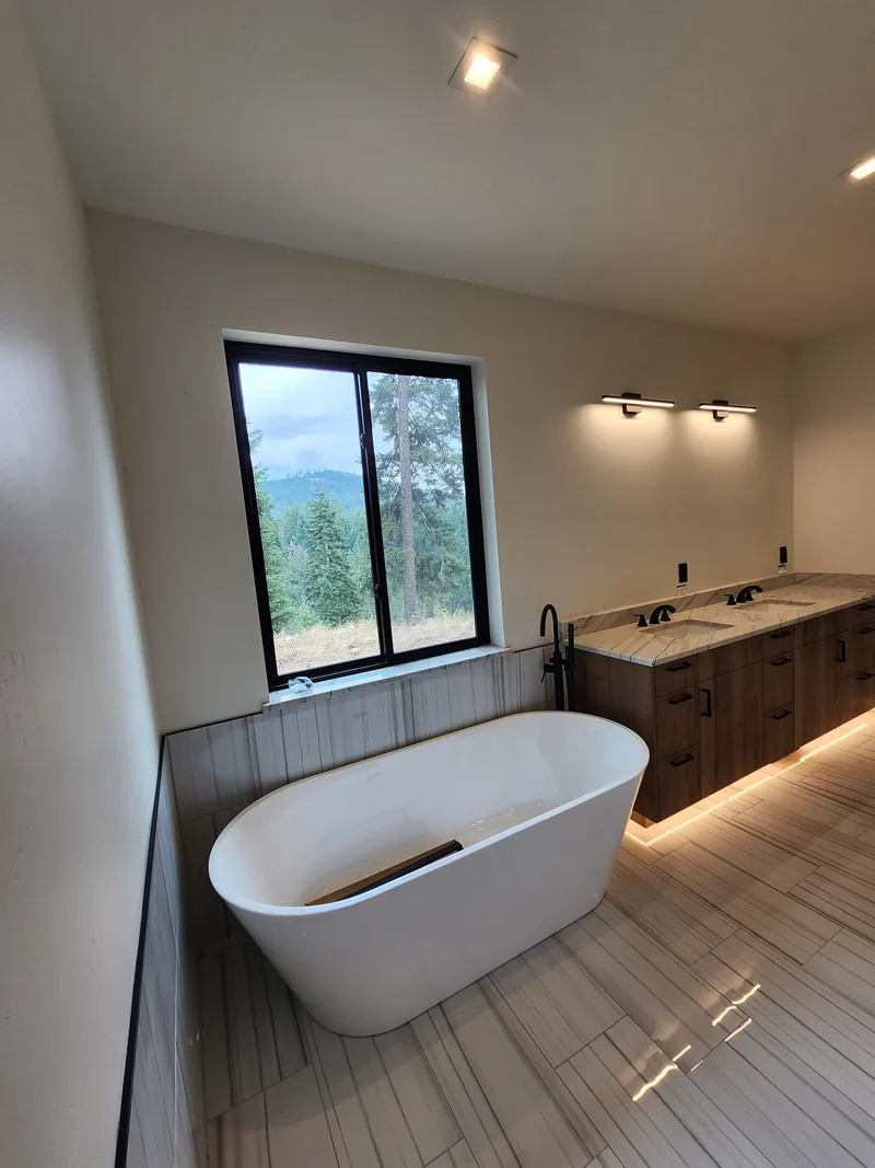 Modern bathroom with a freestanding tub, vanity lighting and a window looking out to the mountains