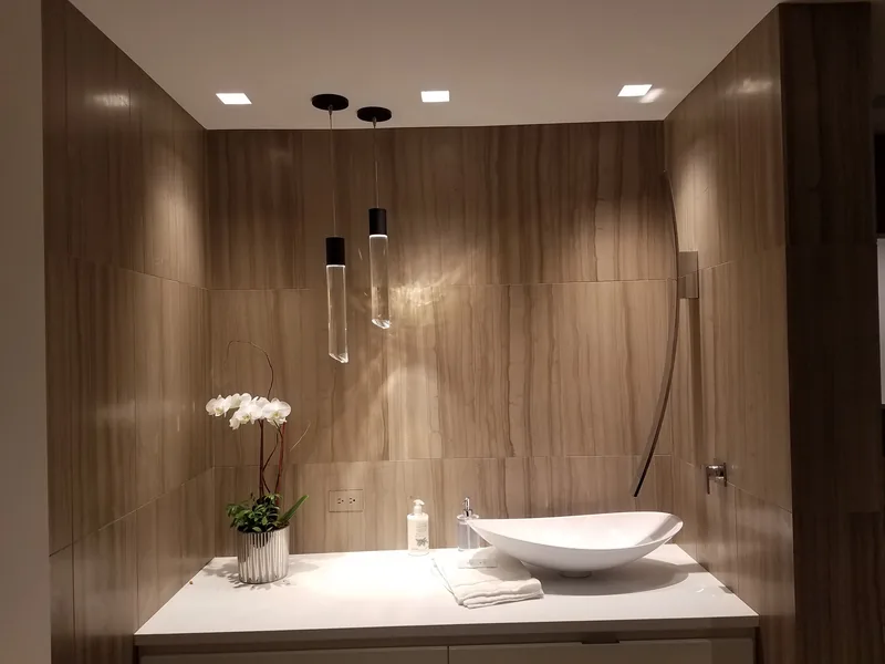 Bathroom with stone walls and pendant lights hung over a vessel sink