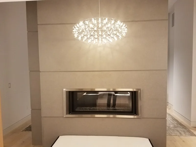 Crystal chandelier hung above a linear gas fireplace, wired by Northwest Wattage