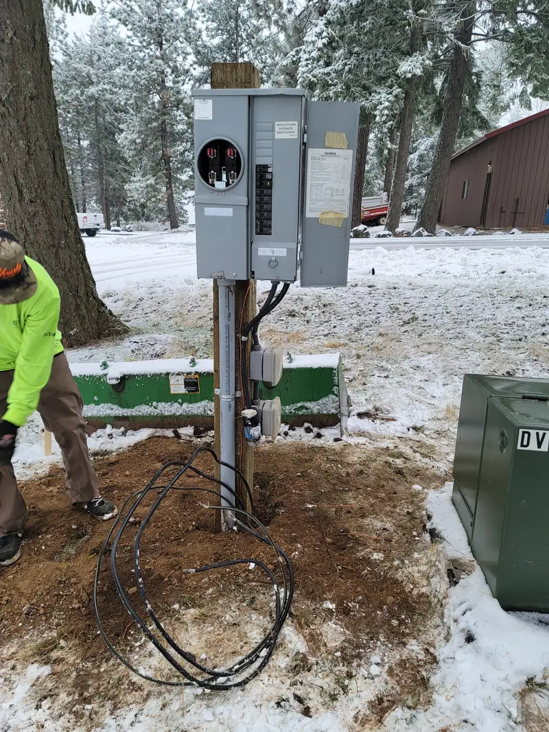Northwest Wattage electrician installing an electrical meter and panel pedestal in winter conditions