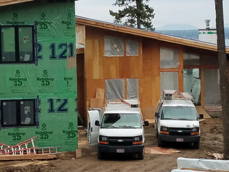 New construction site in North Idaho with Northwest Wattage service vans parked during electrical rough-in