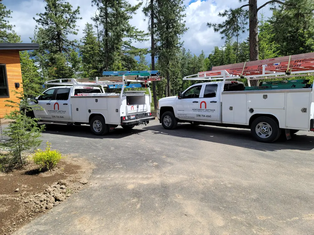 Two branded Northwest Wattage service trucks parked at a job site in the pines near Coeur d'Alene, Idaho