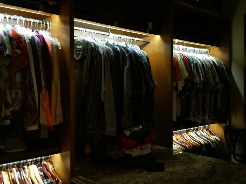 Large walk-in closet with lit hanging rails wired by Northwest Wattage
